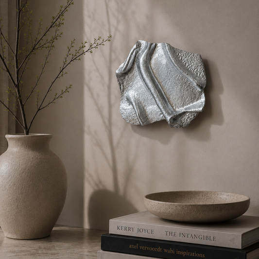 Abstrakt vægkunst i håndformet, chromefarvet aluminium med bløde, organiske linjer og en højglans finish. De reflekterende overflader skaber et levende udtryk, der ændrer sig med lyset.