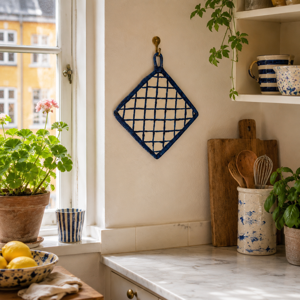 Den dekorative porcelænsgrydelap skaber et varmt og personligt udtryk i køkkenet.
