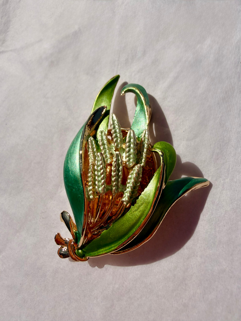 Elegant grøn blomsterbroche med dekorative emaljedetaljer