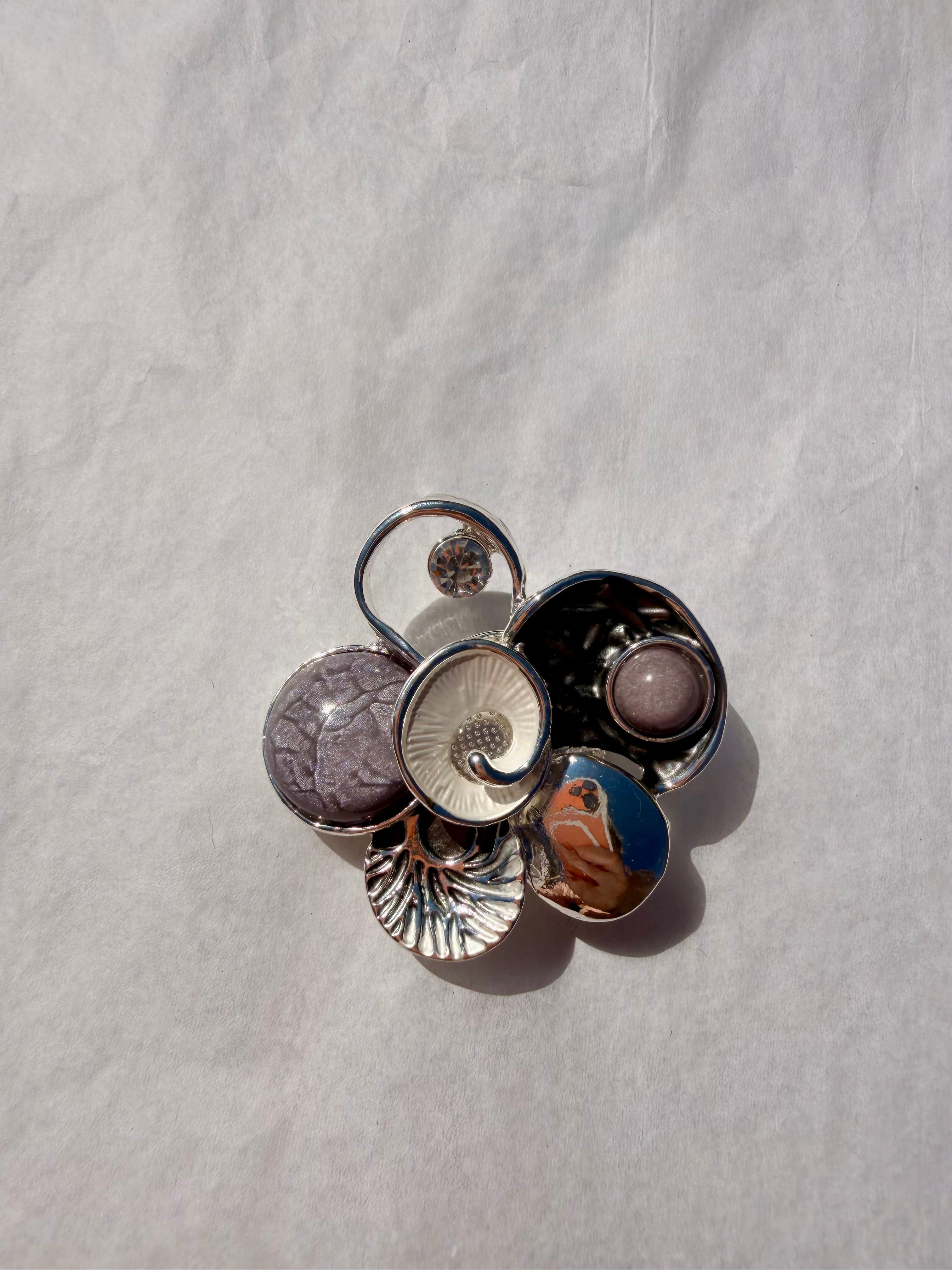 Elegant kunstbroche med dekorative former i grå og sølv