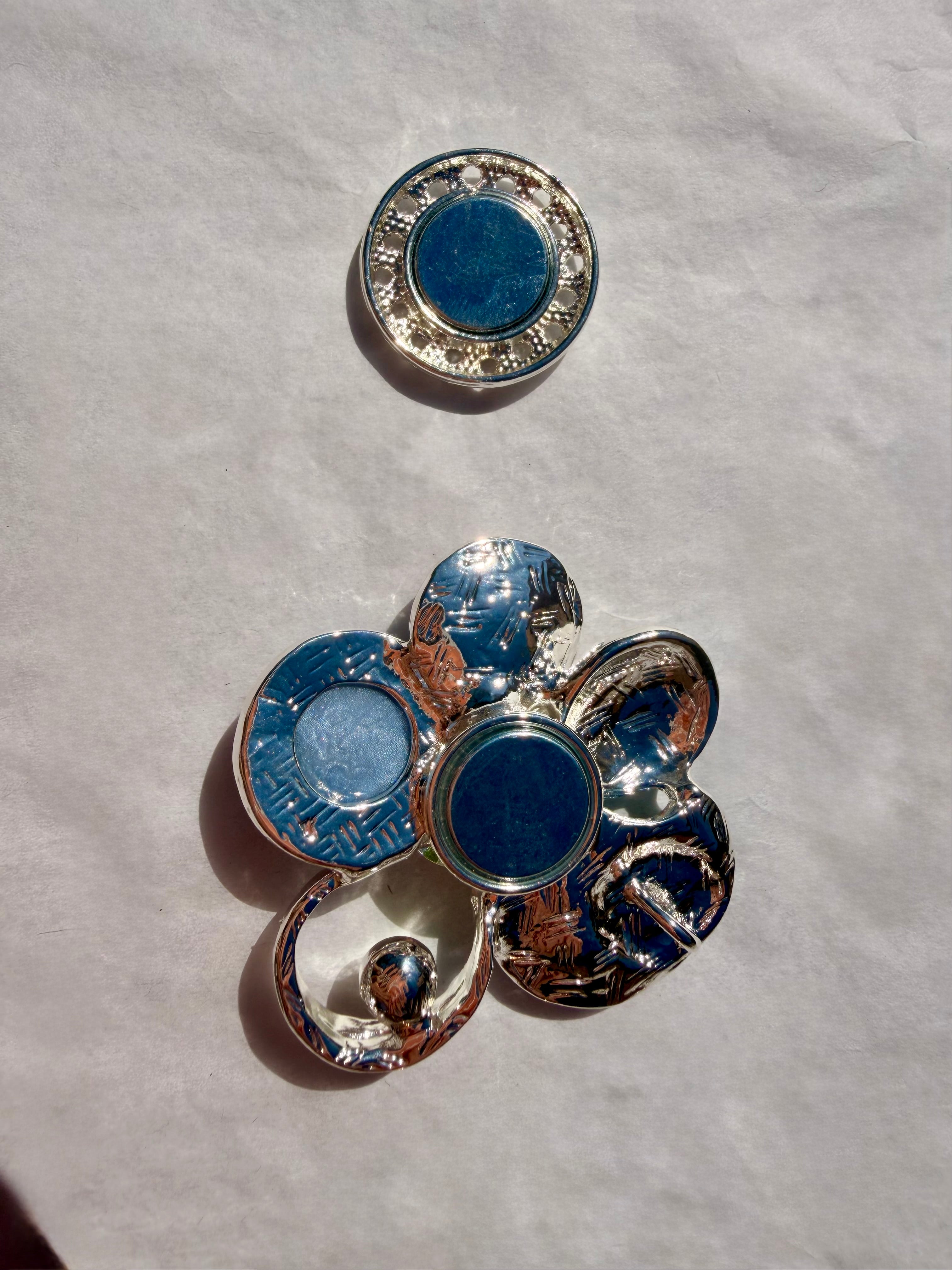 Elegant kunstbroche med dekorative former i lilla og sølv