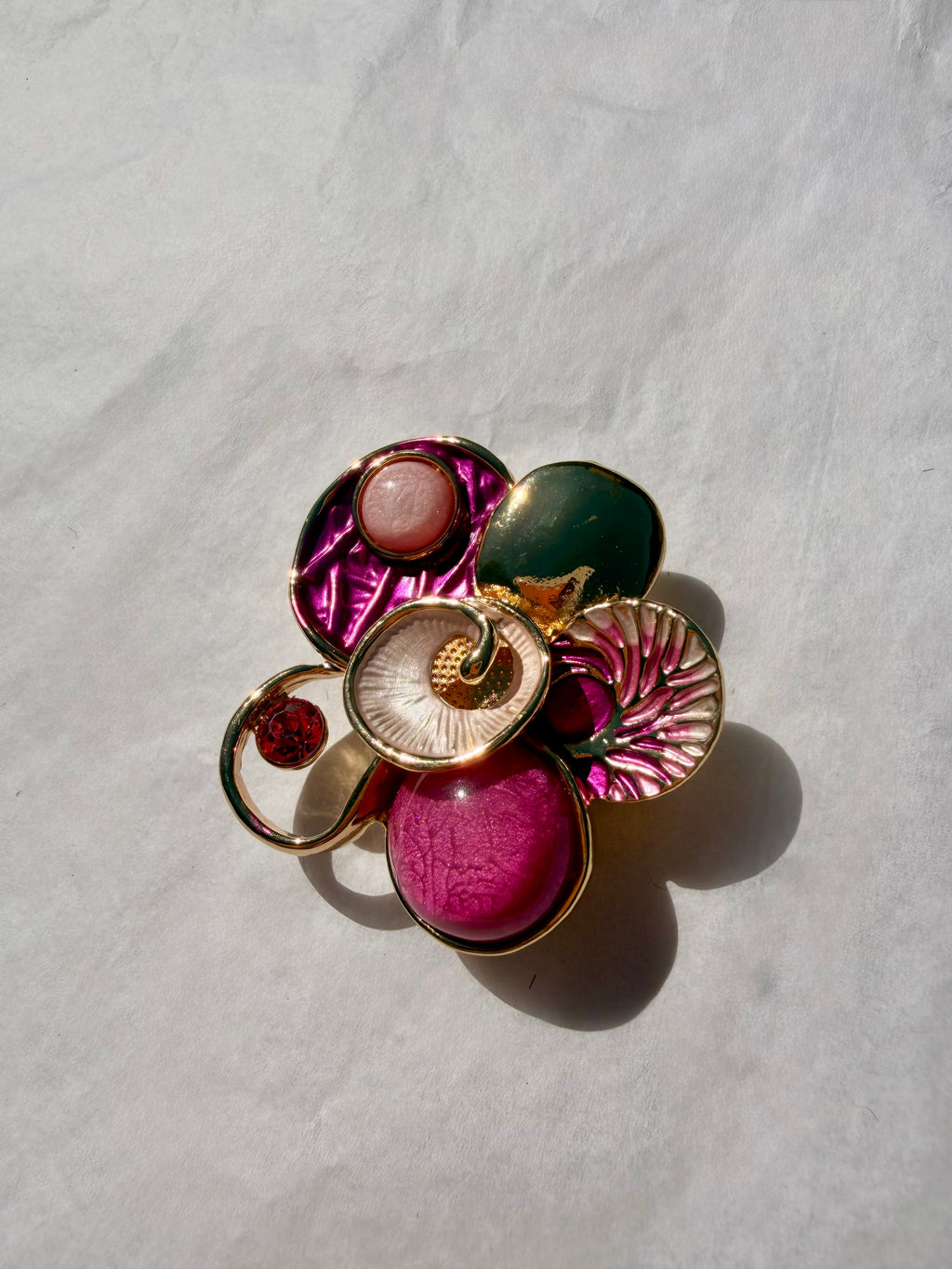 Guldfarvet kunstbroche med pink detaljer