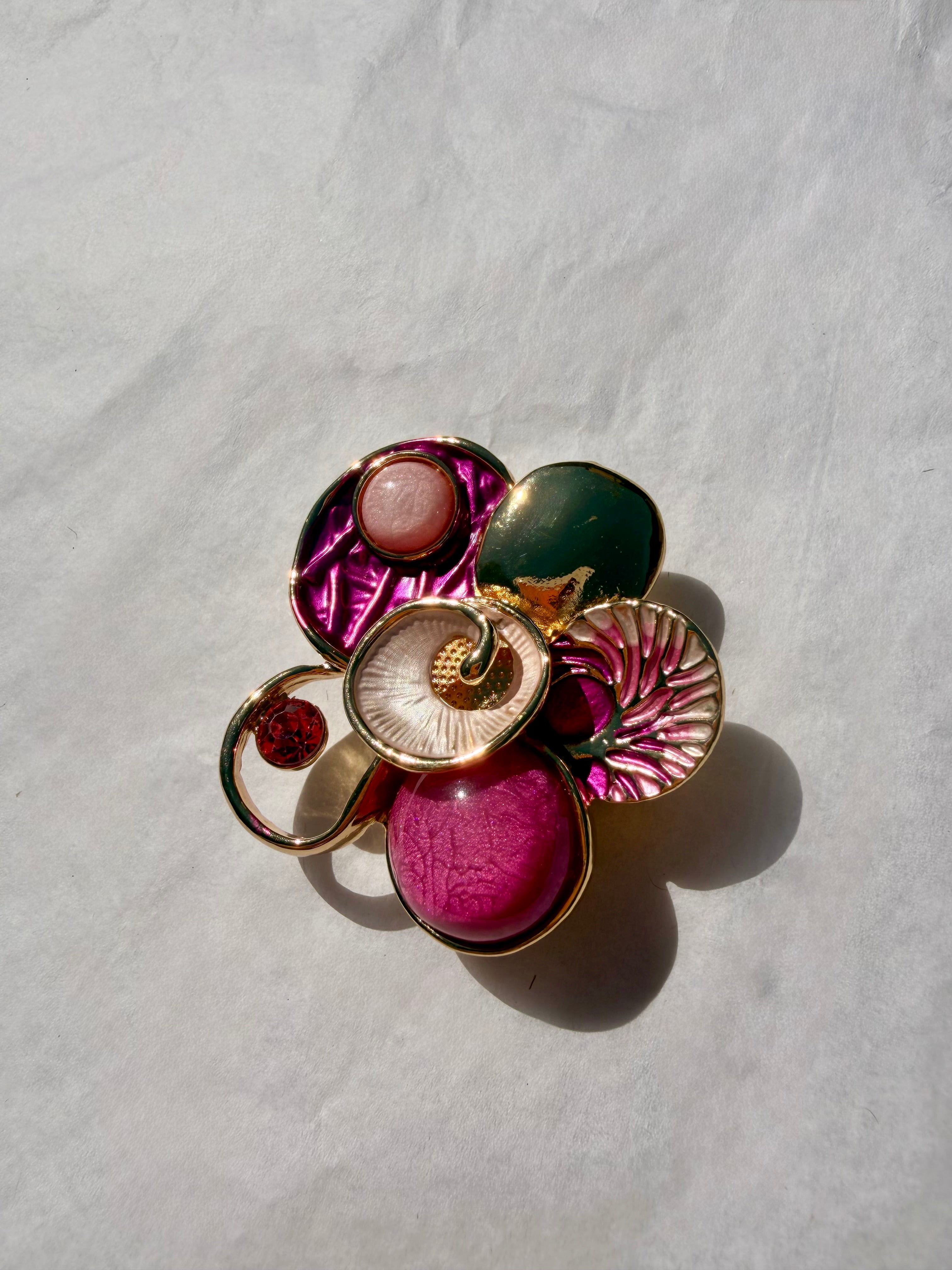 Guldfarvet kunstbroche med pink detaljer