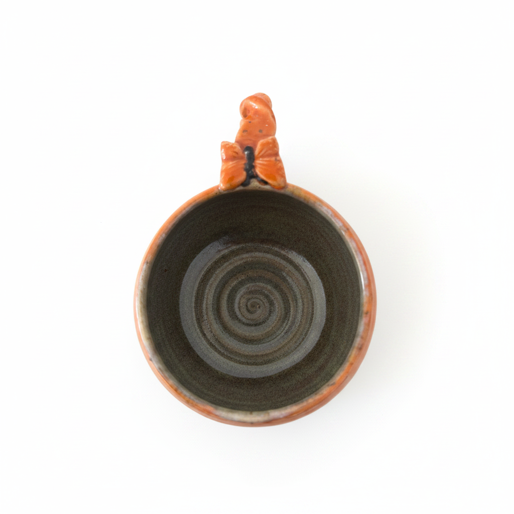 Håndlavet orange keramikkop set oppefra med smuk reaktiv glasur og dekorativ flettet hank i unikt håndlavet design.