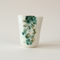 Håndlavet porcelænskrus med grøn marmoreret glasur og kunstnerisk botanisk udtryk.