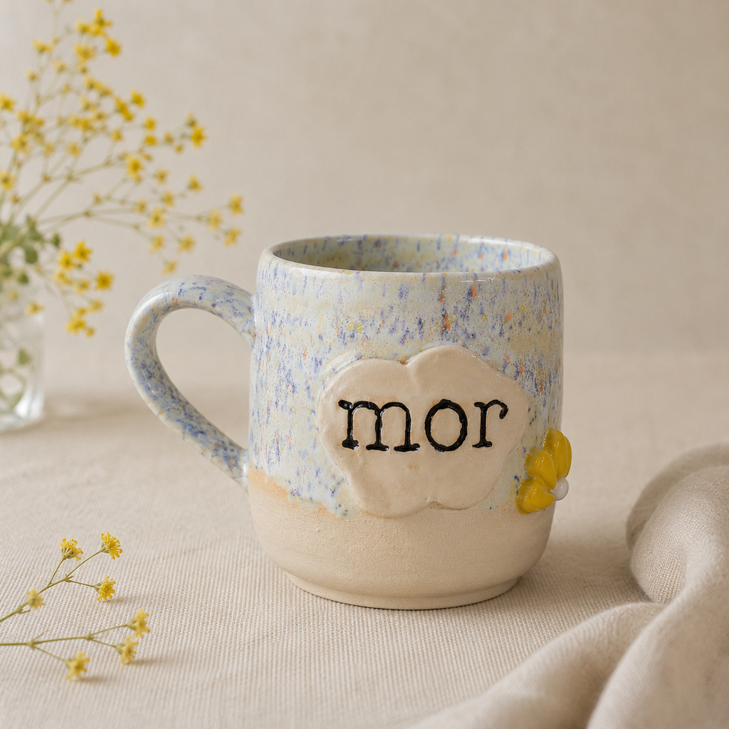 Håndlavet stentøjskop med teksten “mor” og gul blomsterdetalje i bløde lyse nuancer.