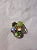 Kunstnerisk broche med grønne nuancer og metallisk finish
