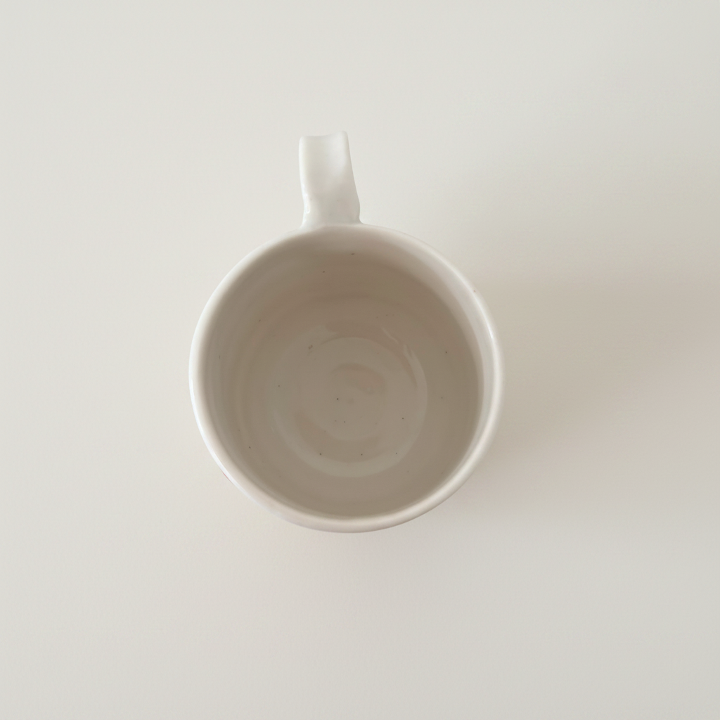 Minimalistisk håndlavet porcelænskrus set ovenfra med blank glasur og elegant rund form.
