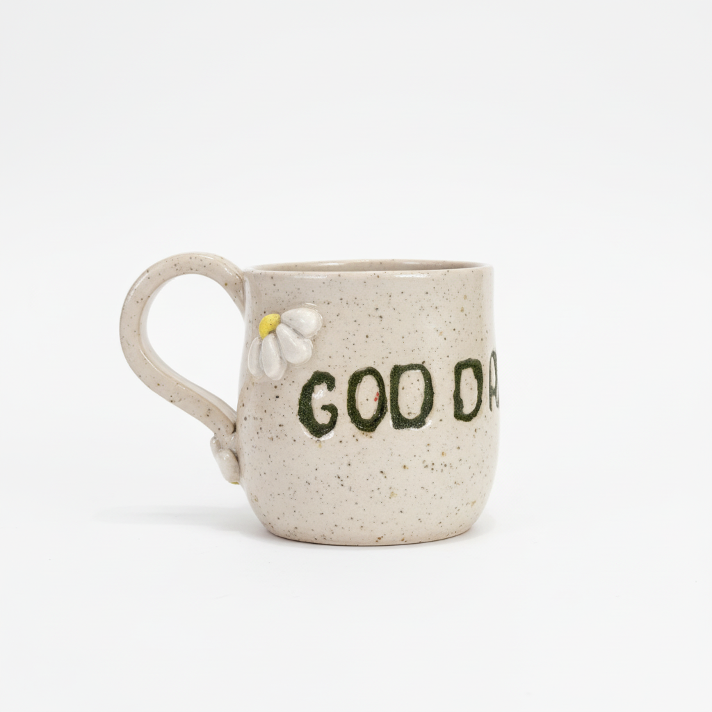 Minimalistisk produktbillede af keramikkop med blomsterdetaljer og teksten “Good day”