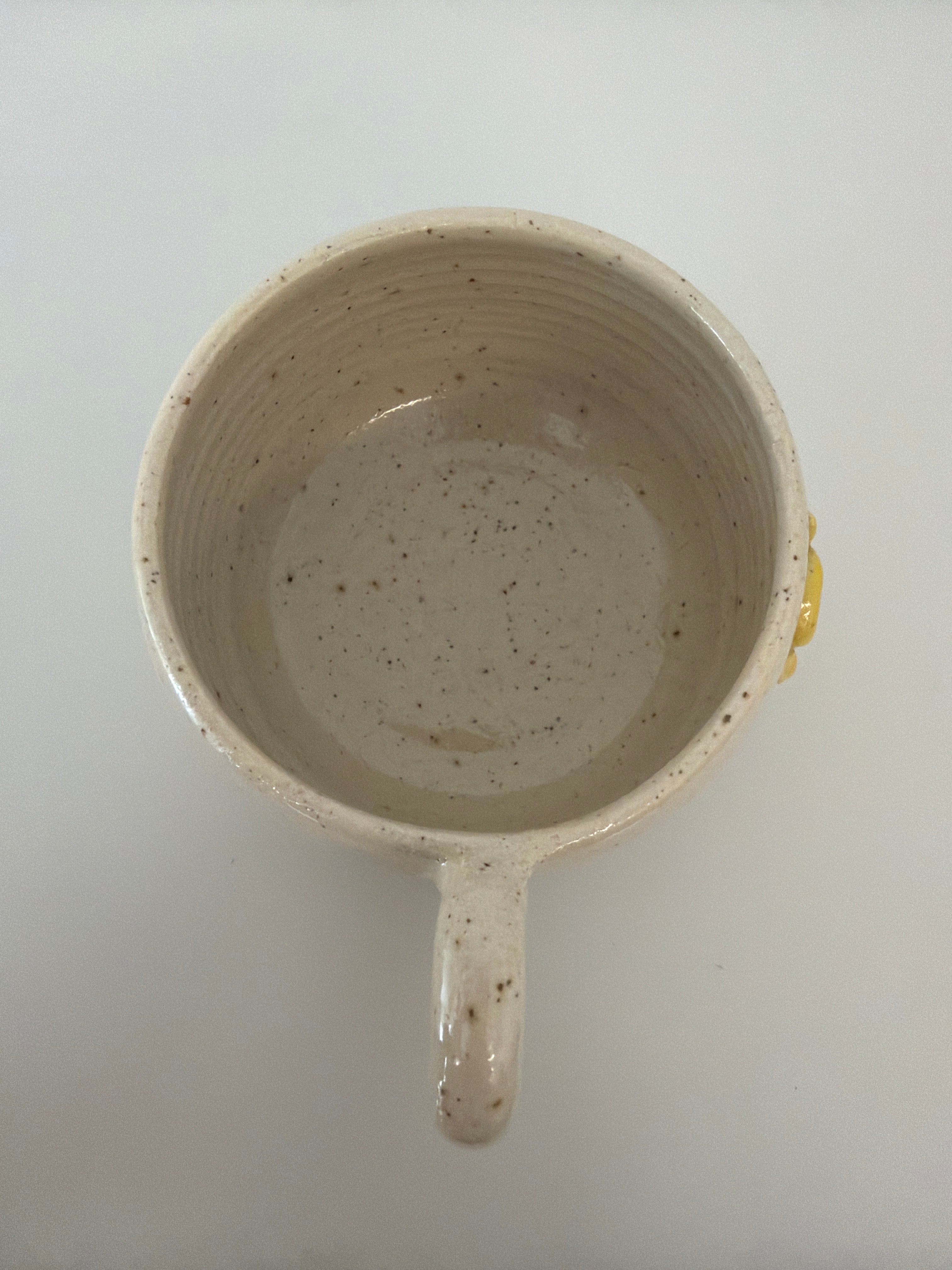 Topbillede af håndlavet keramikkrus i lyst stentøj med fine naturlige detaljer og blank glasur.